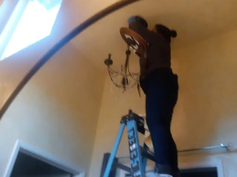 Electrician installing a chandelier in a Stillwater residence